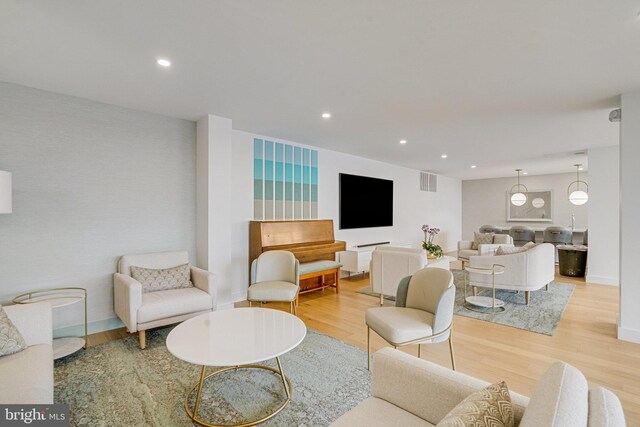 living area with wood finished floors, visible vents, and recessed lighting