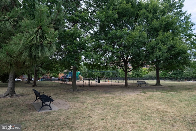 view of property's community featuring a lawn, fence, and playground community