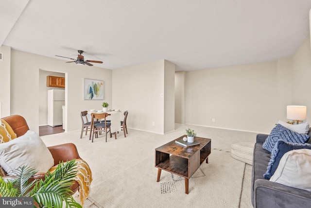 carpeted living room featuring a ceiling fan and baseboards