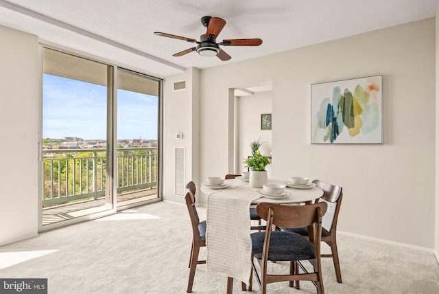 carpeted dining area featuring expansive windows, visible vents, and ceiling fan