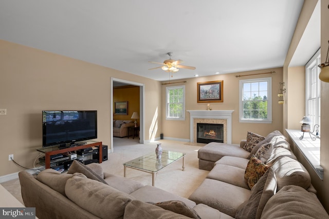 living area featuring baseboards, light carpet, a ceiling fan, and a premium fireplace