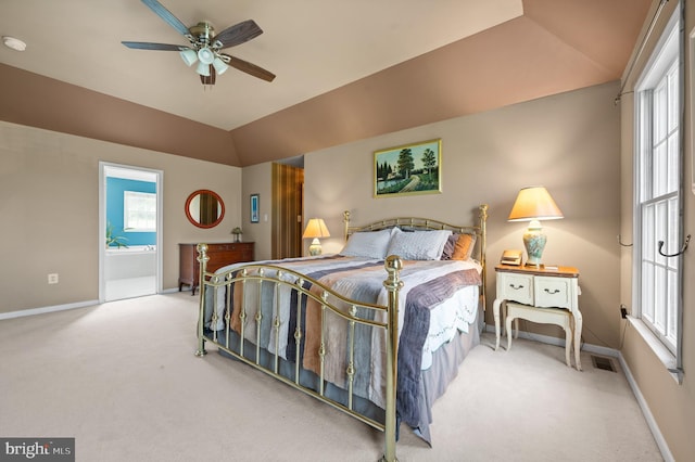 carpeted bedroom with baseboards, vaulted ceiling, multiple windows, and ensuite bathroom