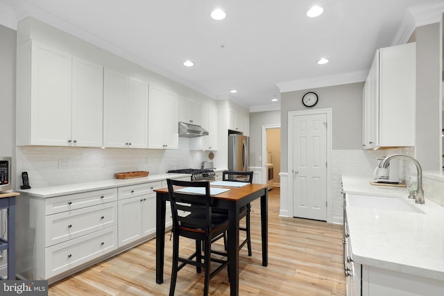 84 Battery Point Dr, Fredericksburg, VA 22406 - kitchen with under cabinet range hood, a sink, ornamental molding, backsplash, and appliances with stainless steel finishes
