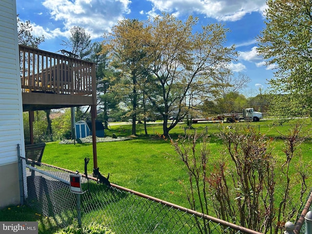view of yard featuring an outbuilding, fence, a wooden deck, and a storage unit