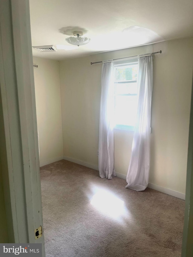 carpeted empty room featuring visible vents and baseboards