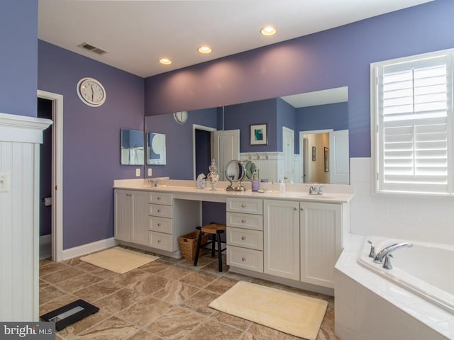 bathroom with plenty of natural light, a garden tub, visible vents, and vanity