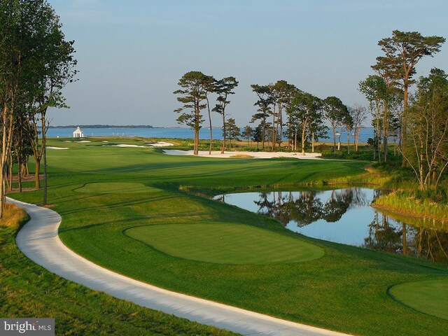 view of home's community featuring golf course view, a lawn, and a water view