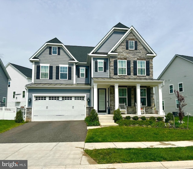 craftsman inspired home with an attached garage, stone siding, a standing seam roof, a porch, and driveway