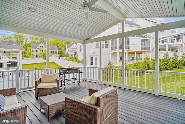 wooden terrace featuring a lawn, ceiling fan, fence, and a residential view