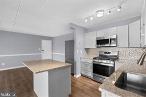 9201 New Hampshire Ave Unit 302, Silver Spring, MD 20903 - kitchen featuring white cabinets, stainless steel appliances, a sink, a kitchen island, and decorative backsplash