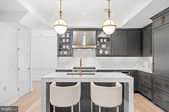kitchen featuring backsplash, light countertops, wall chimney range hood, and ornamental molding