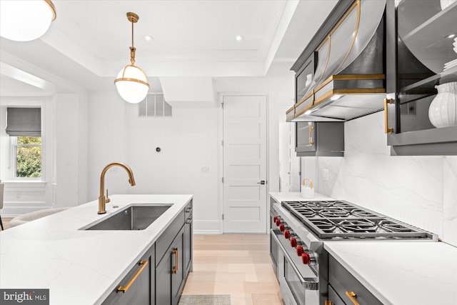 kitchen with high end stainless steel range, a raised ceiling, visible vents, a sink, and light stone countertops