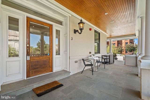 property entrance with a porch and brick siding