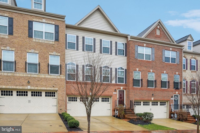 multi unit property with brick siding, a garage, and driveway