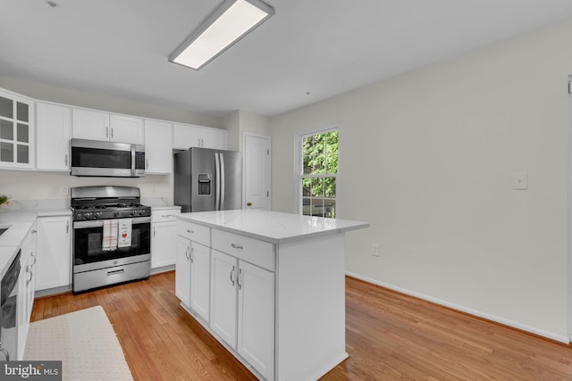 kitchen with light wood-style floors, appliances with stainless steel finishes, white cabinets, and glass insert cabinets