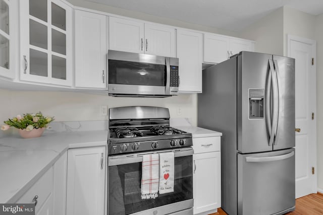 kitchen with glass insert cabinets, appliances with stainless steel finishes, and white cabinetry