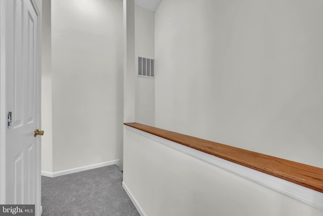 hallway featuring carpet floors, baseboards, and visible vents
