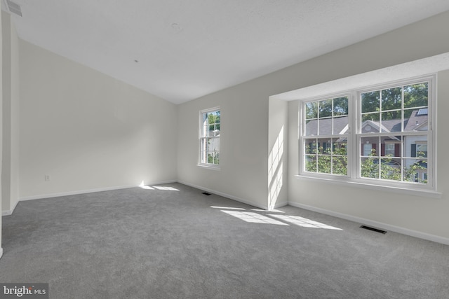 carpeted spare room featuring visible vents, baseboards, and vaulted ceiling