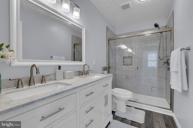 bathroom featuring a textured ceiling, visible vents, a shower stall, and a sink