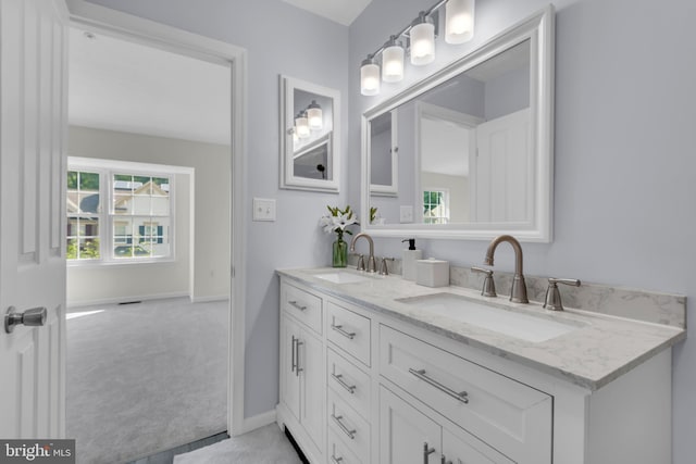 bathroom featuring a sink, baseboards, and double vanity
