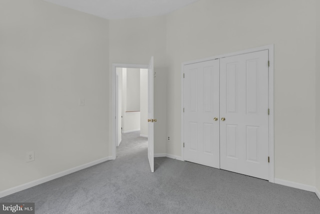unfurnished bedroom with baseboards, carpet, and a closet