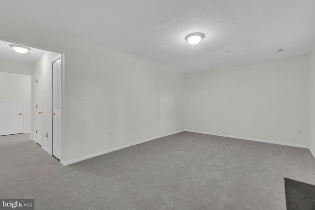 carpeted empty room with a textured ceiling and baseboards