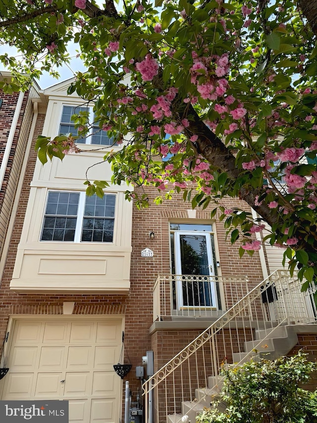multi unit property with an attached garage and brick siding