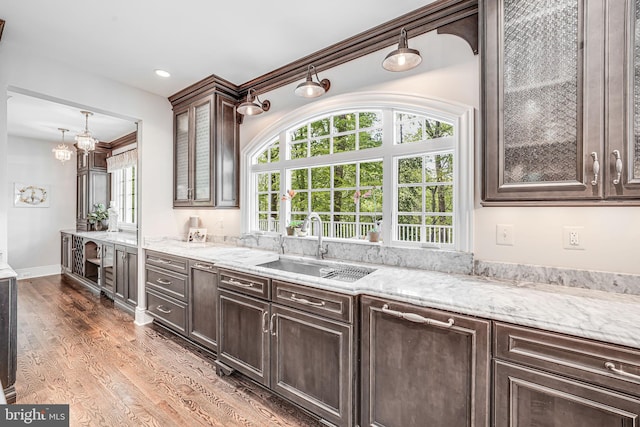 6020 Copely Ln, Mclean, VA 22101 - kitchen featuring an inviting chandelier, dark brown cabinetry, light stone countertops, a sink, and glass insert cabinets