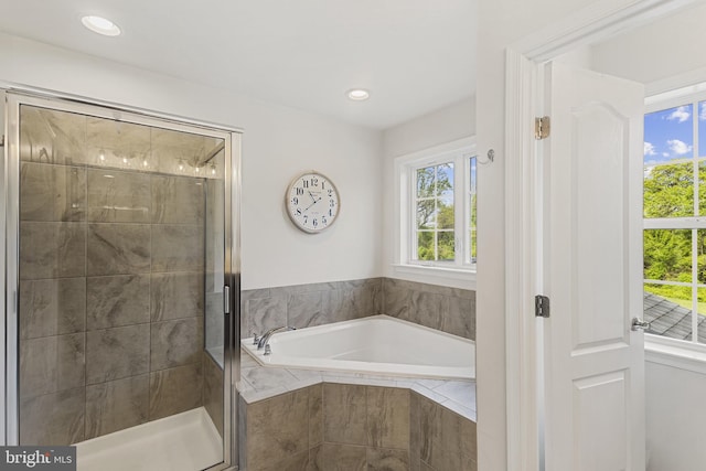 bathroom with a garden tub, a stall shower, and a healthy amount of sunlight