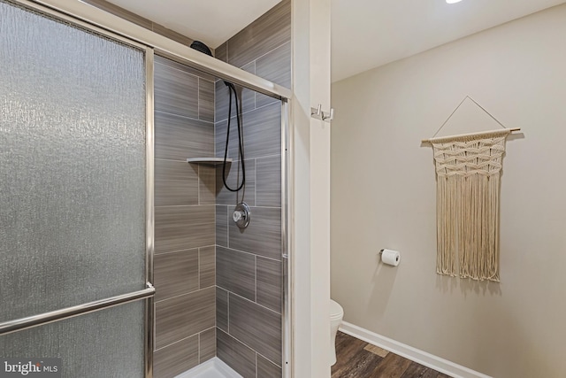 bathroom featuring toilet, a shower stall, wood finished floors, and baseboards