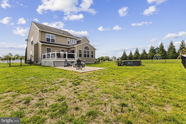 rear view of property featuring a patio, a wooden deck, a lawn, and a fenced backyard