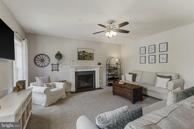 living area with a fireplace with flush hearth, ceiling fan, baseboards, and carpet floors