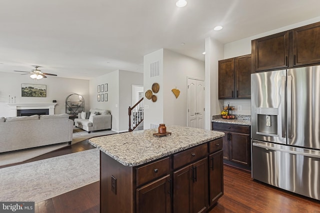 kitchen with stainless steel fridge, a center island, visible vents, a ceiling fan, and open floor plan