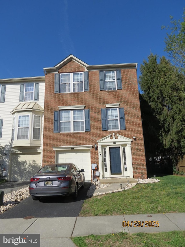 view of front of property featuring brick siding, a front yard, a garage, and aphalt driveway