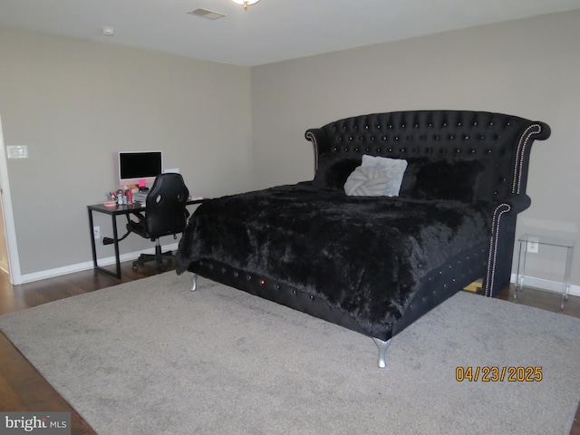 bedroom with baseboards, wood finished floors, and visible vents