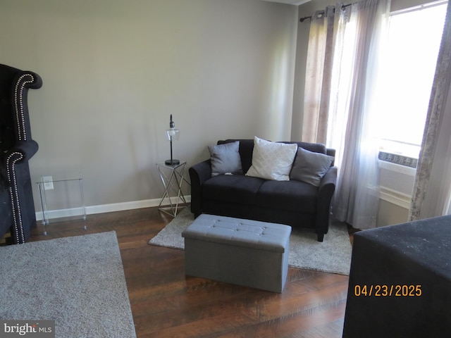living area featuring cooling unit, wood finished floors, a healthy amount of sunlight, and baseboards