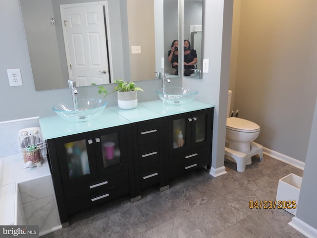 full bath with double vanity, toilet, baseboards, and a sink