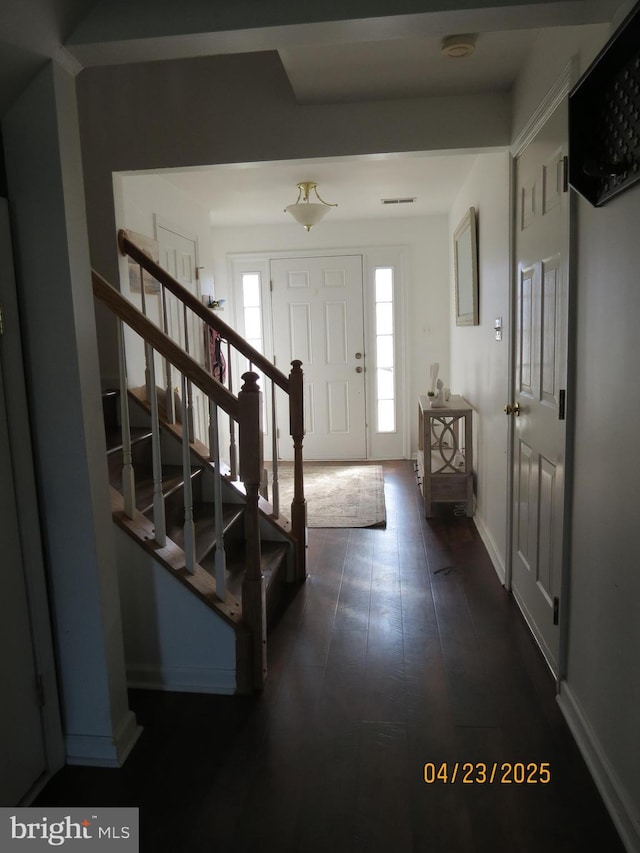 foyer featuring dark wood finished floors, baseboards, and stairs