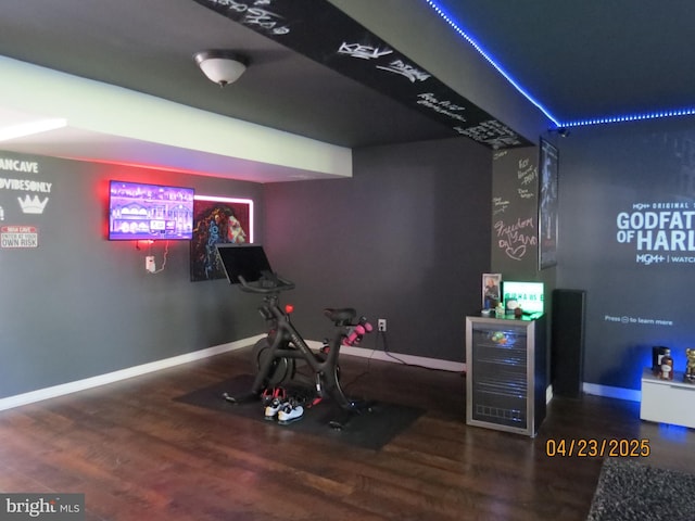 workout area featuring baseboards, wood finished floors, and beverage cooler