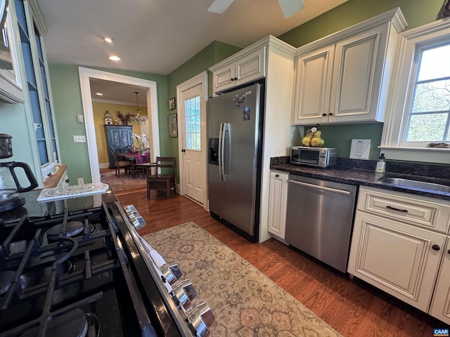 kitchen with a toaster, a sink, dark stone counters, dark wood finished floors, and appliances with stainless steel finishes