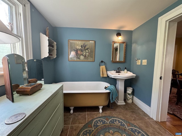 bathroom with a freestanding bath, baseboards, and tile patterned floors