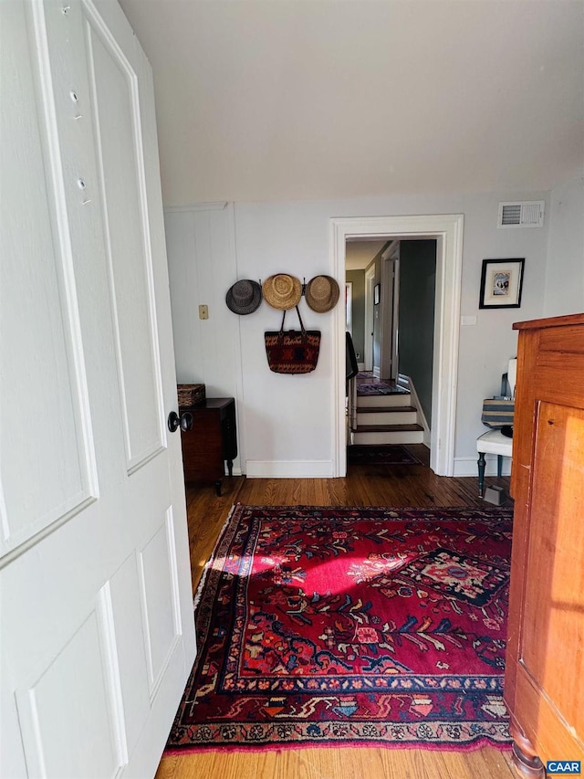 hallway featuring baseboards, wood finished floors, and visible vents