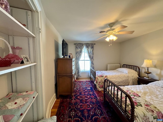 bedroom with radiator heating unit, a ceiling fan, baseboards, and dark wood-type flooring