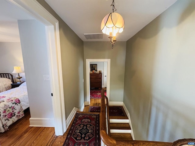 hall with baseboards, wood finished floors, and visible vents