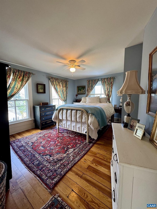 bedroom with wood-type flooring, ceiling fan, and multiple windows