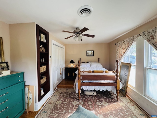 bedroom with a closet, wood finished floors, visible vents, and a ceiling fan