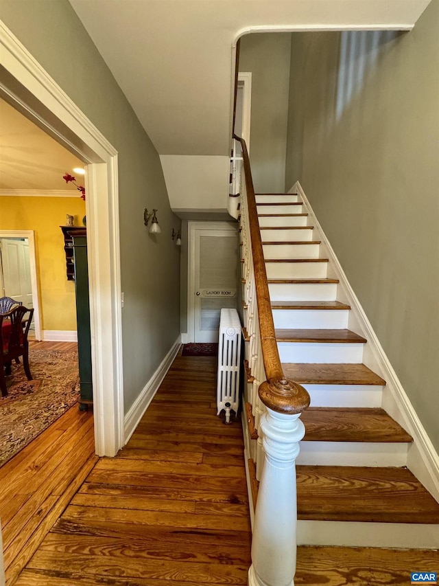stairs featuring radiator, baseboards, and wood finished floors