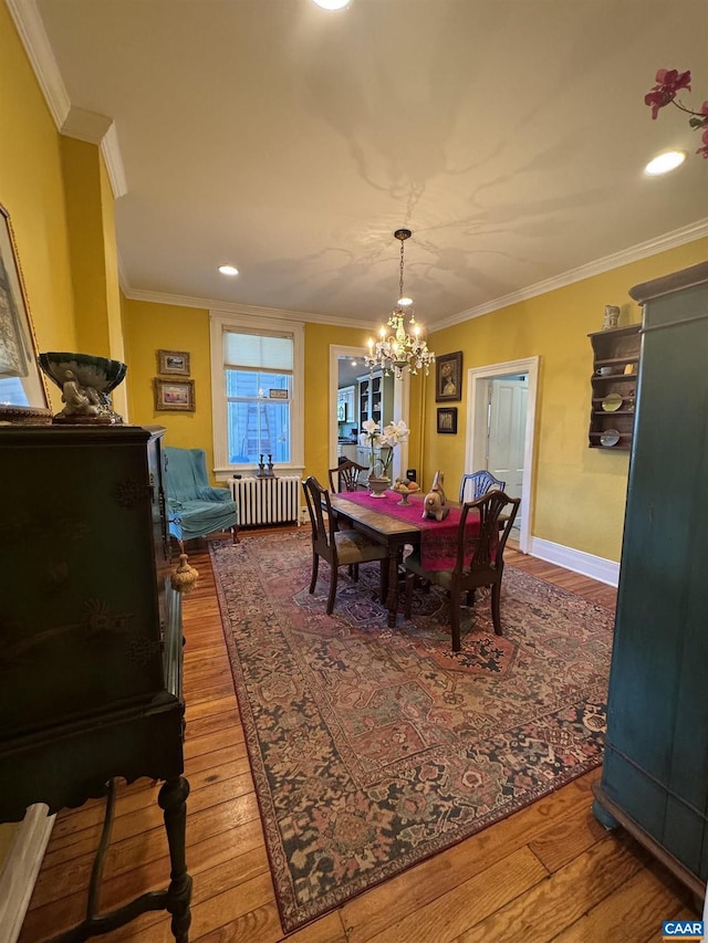 dining area with wood finished floors, an inviting chandelier, ornamental molding, and radiator