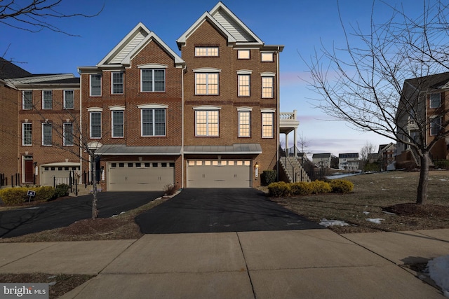 view of property with brick siding, an attached garage, and driveway