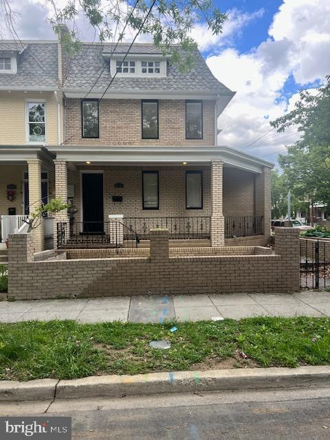 view of front of house featuring brick siding and covered porch